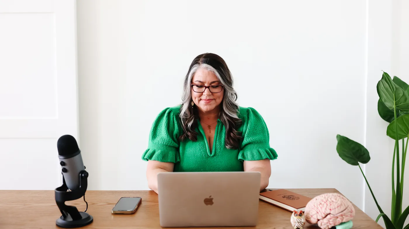 Teresa Lodato at a desk with a laptop and podcast microphone