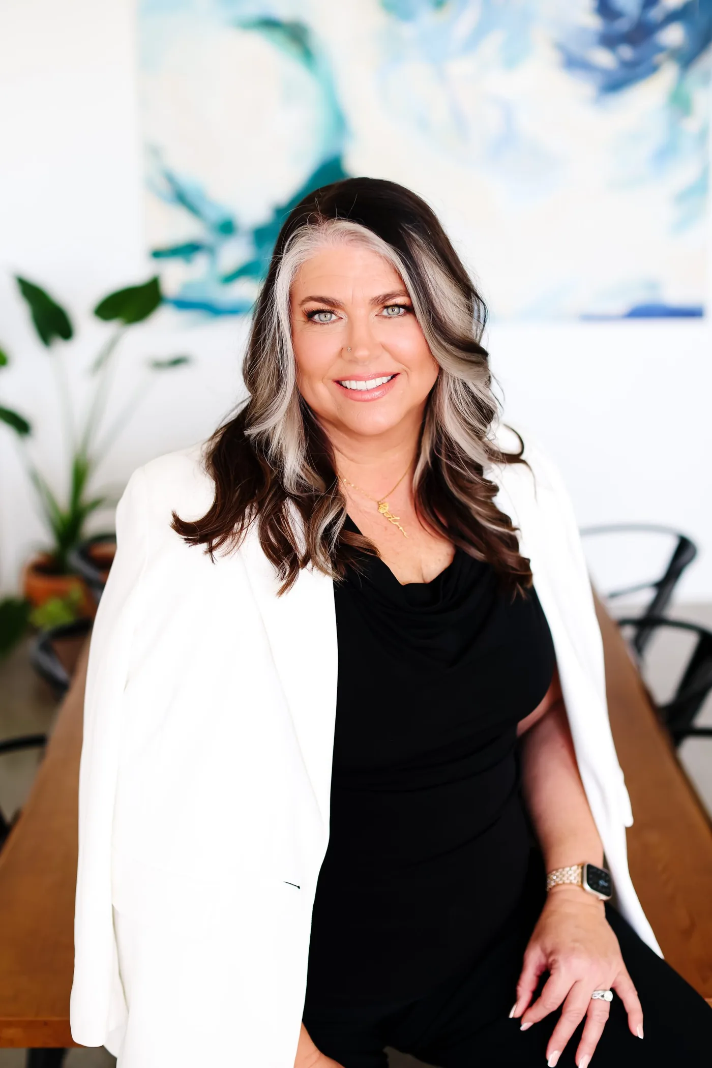 Teresa Lodato in a white blazer, seated in front of an abstract blue painting