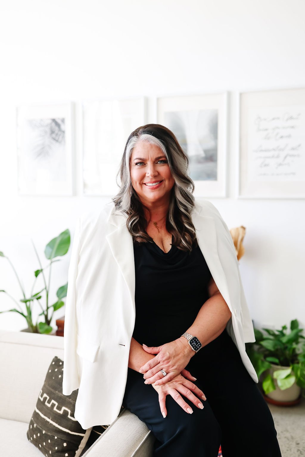 Teresa Lodato seated in a white blazer in a bright room with framed prints