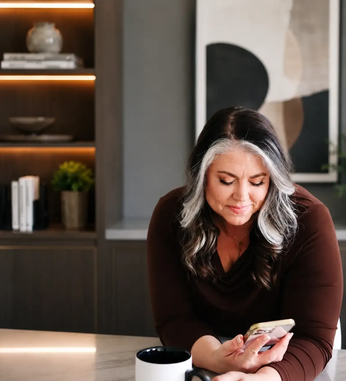 Teresa Lodato looking at her phone in a softly lit office